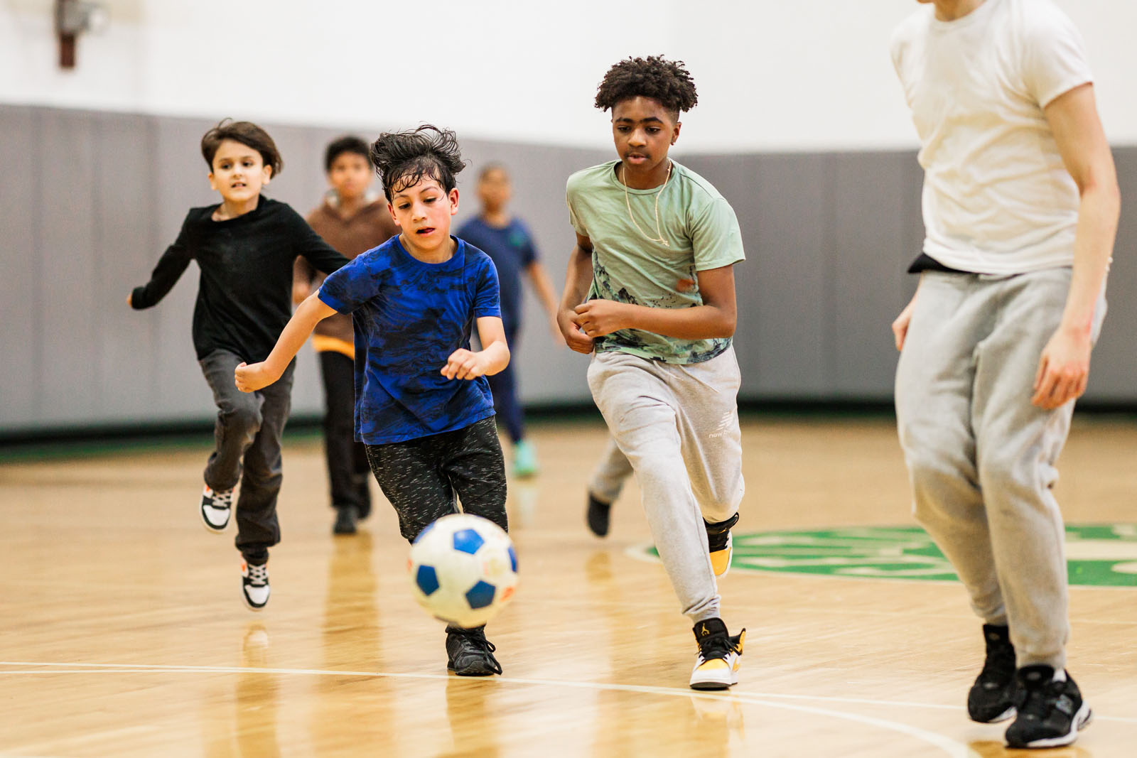 Youth members engaged in a soccer game, their attention on the soccer ball in front of them.