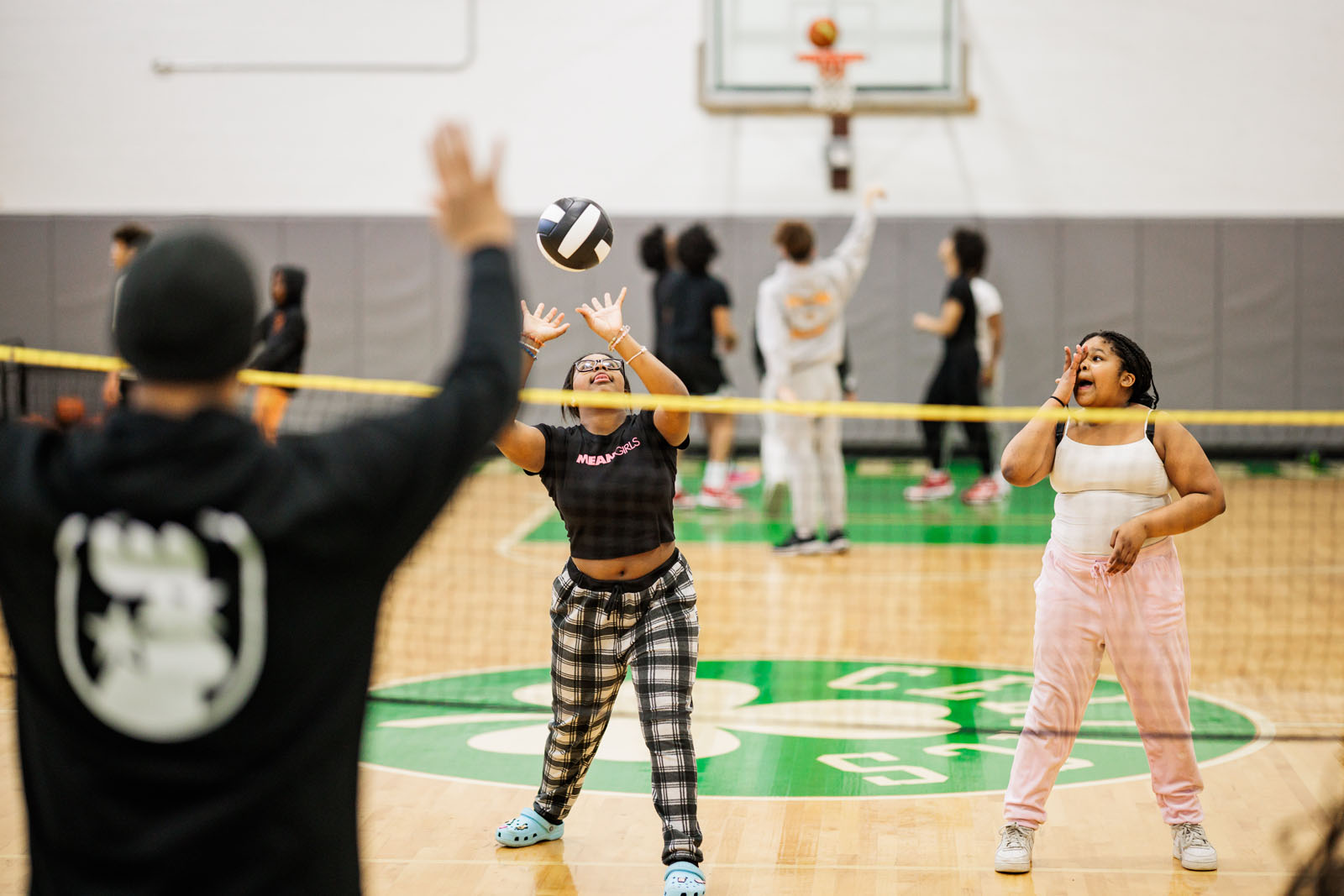 A teen member dynamically sets the volleyball across the net.