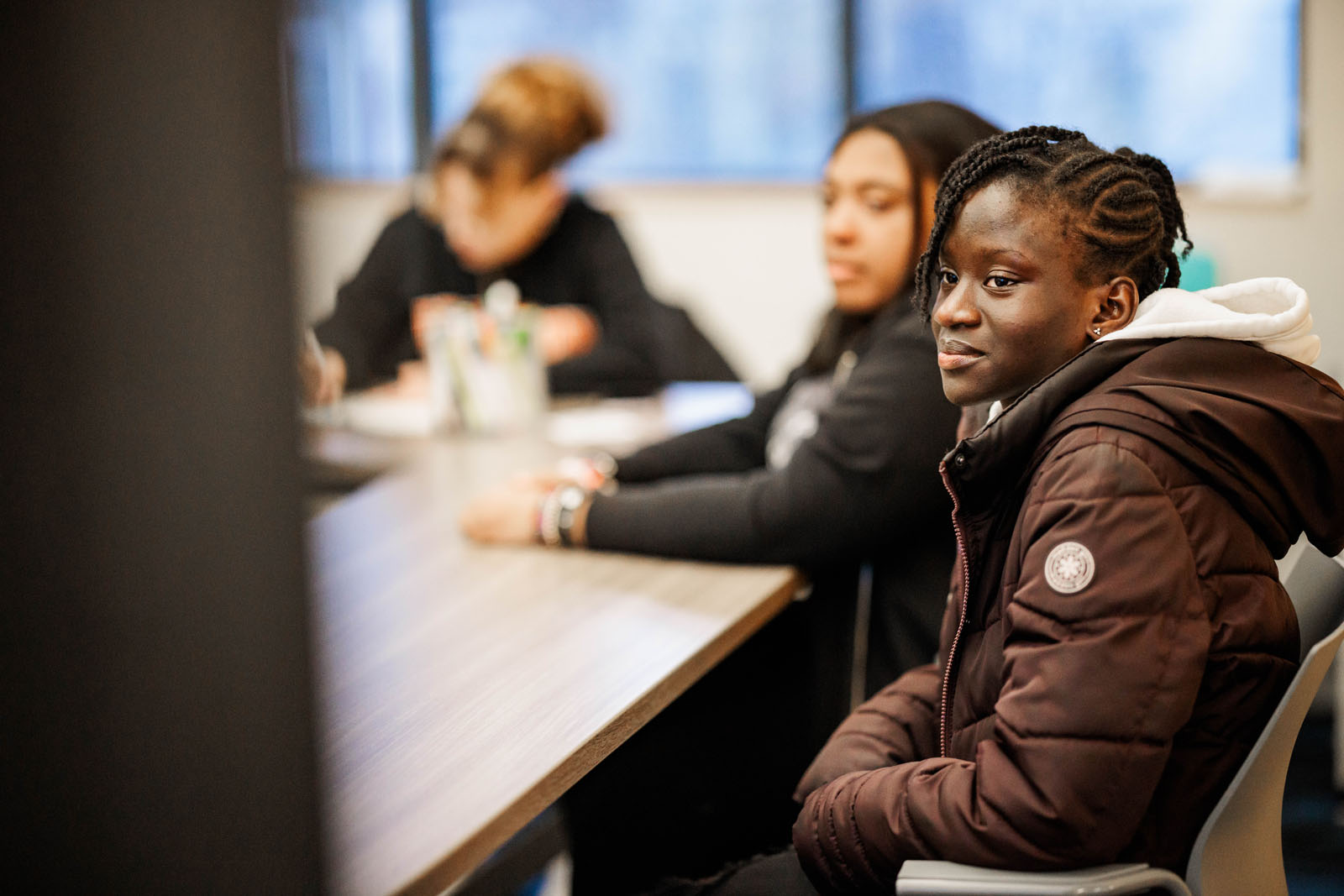 A teen sits attentively, her gaze fixed on one of the group members who is speaking.