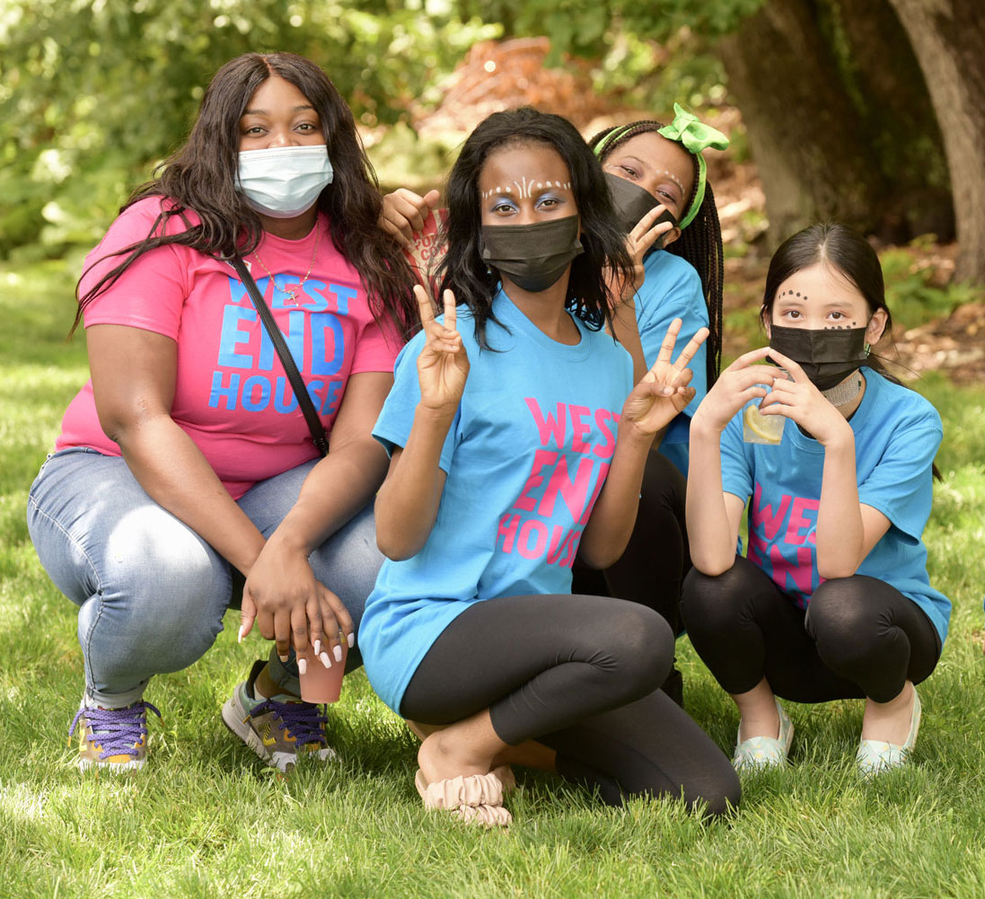 Young people posing at event in colorful West End House t-shirts wearing masks